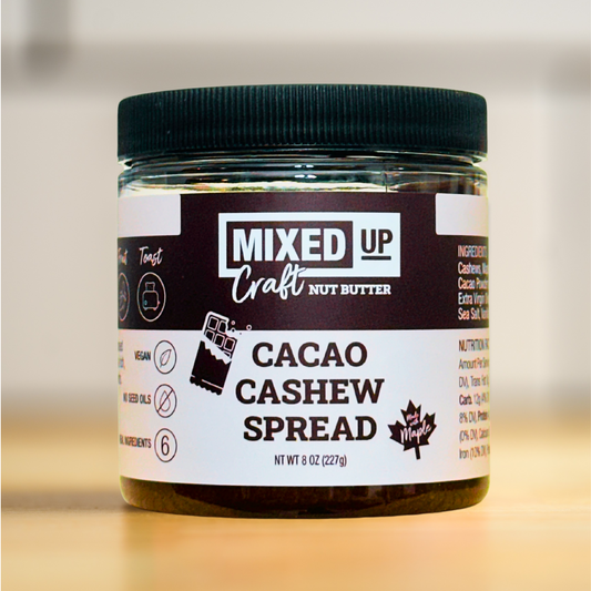 A jar of Cacao Cashew Spread on a kitchen counter, with the label 'MIXED UP Craft Nut Butter' and the product name clearly visible.